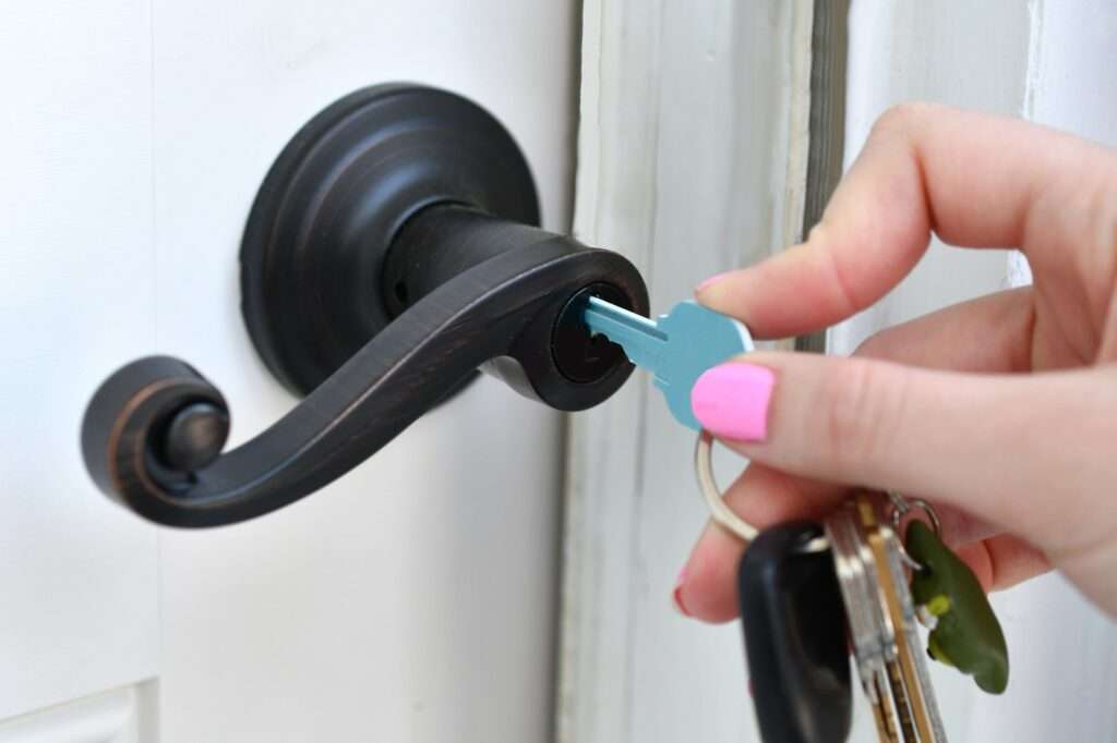 A female using a key to unlock the door.