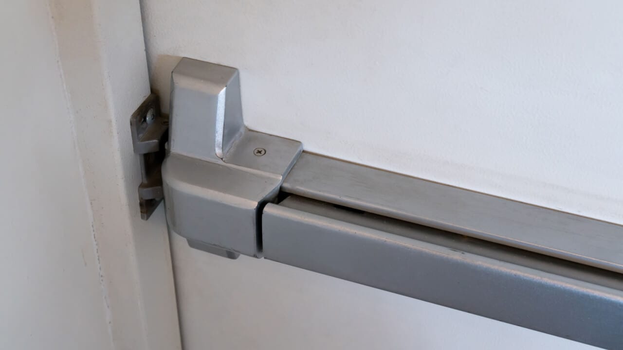 Commercial lock change. Latch and door handle of emergency exit. Push bar and rail for panic exit.