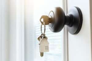 Key ring with a house on it inserted in a front door of a home to unlock a secure entrance.