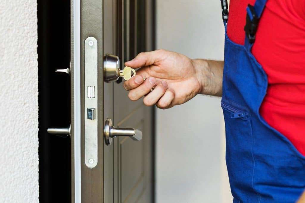 Locksmith working with house door lock. Residential locksmith services.